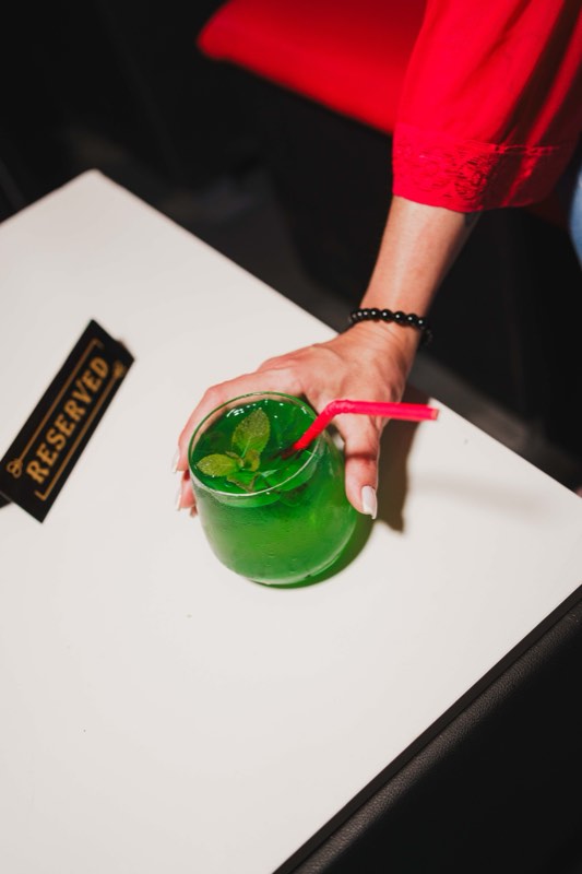 Cocktail verde na mesa, junto a uma placa de reservado