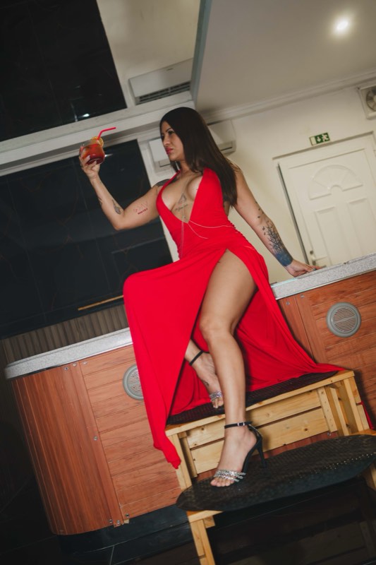 Convidada de vestido vermelho com uma bebida na mão
