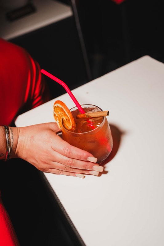 Cocktail de citrinos na mão, numa mesa do bar